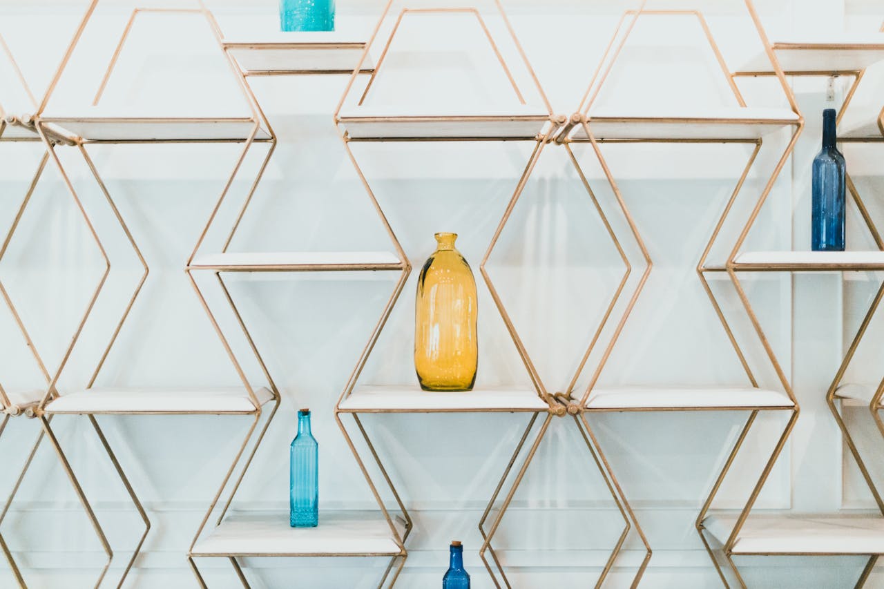 Elegant hexagonal shelves showcasing colorful glass bottles against a white background.