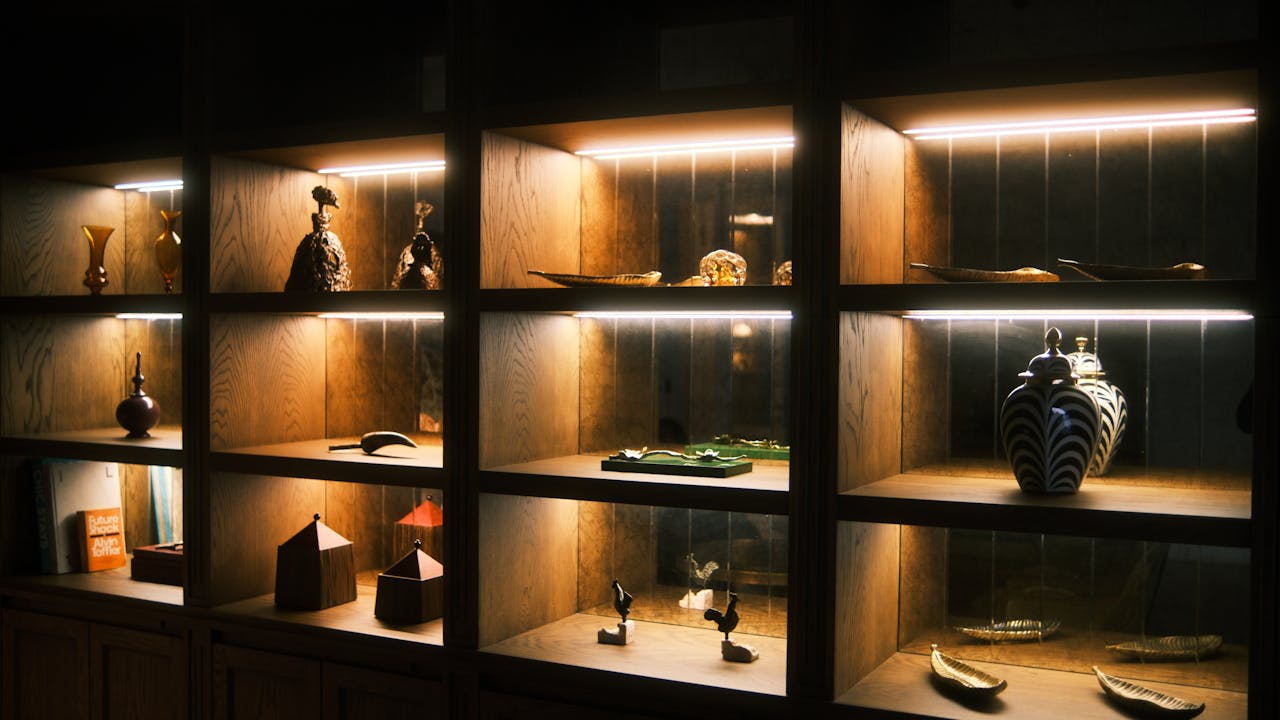 Wooden display shelves with artistic ceramics and sculptures elegantly lit for a warm ambiance.